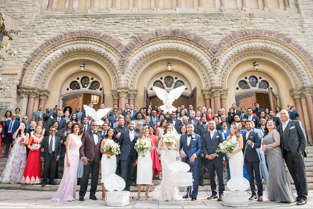 White doves taking flight above a wedding party outside a church