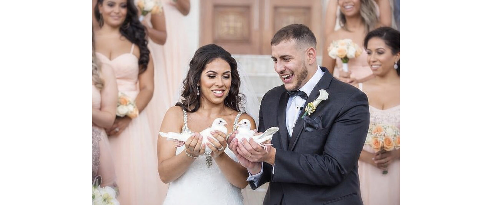 A couple holding two white doves on their wedding day
